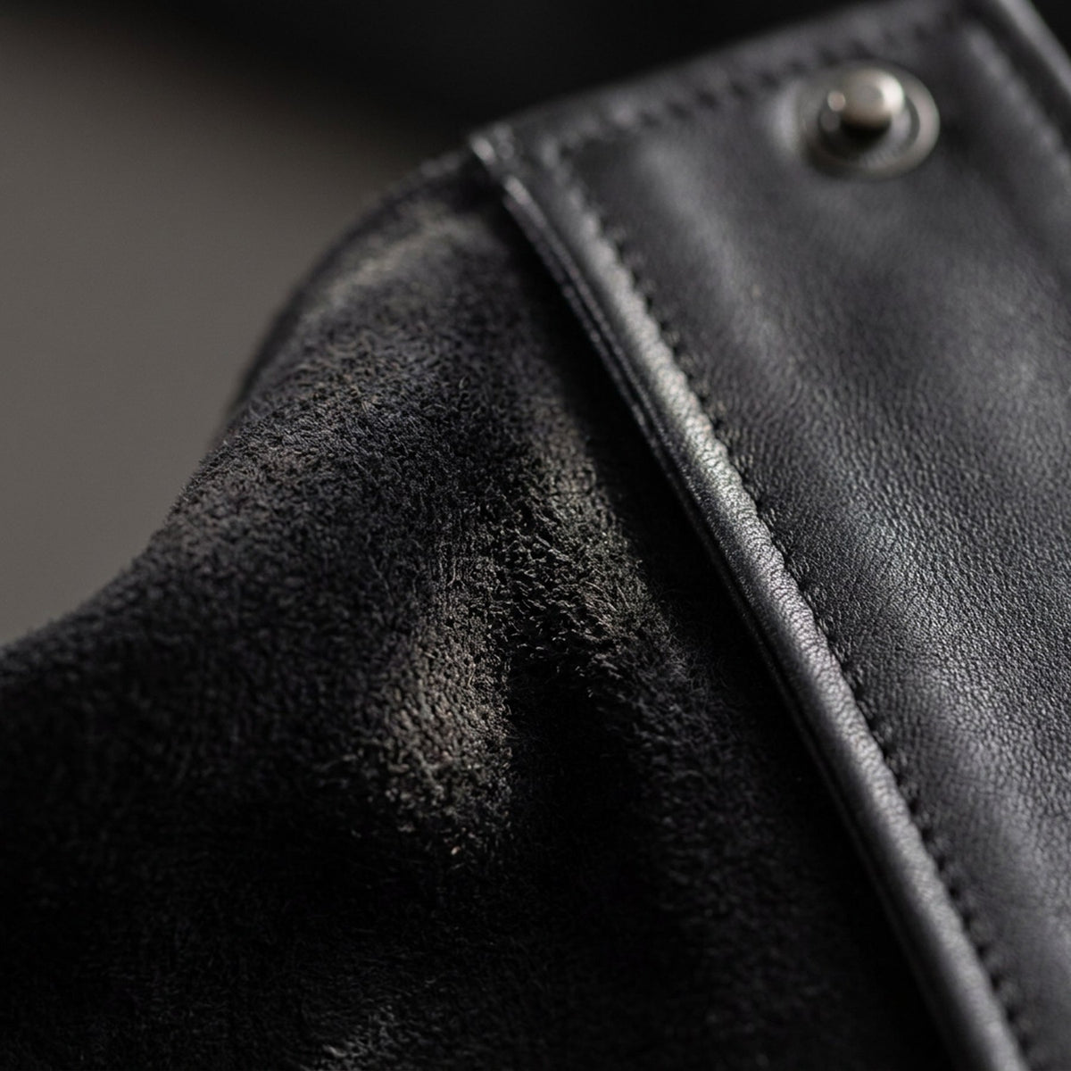 Macro du suède noir et de l'empiècement de cuir, blouson RADICE Maison Godefroi