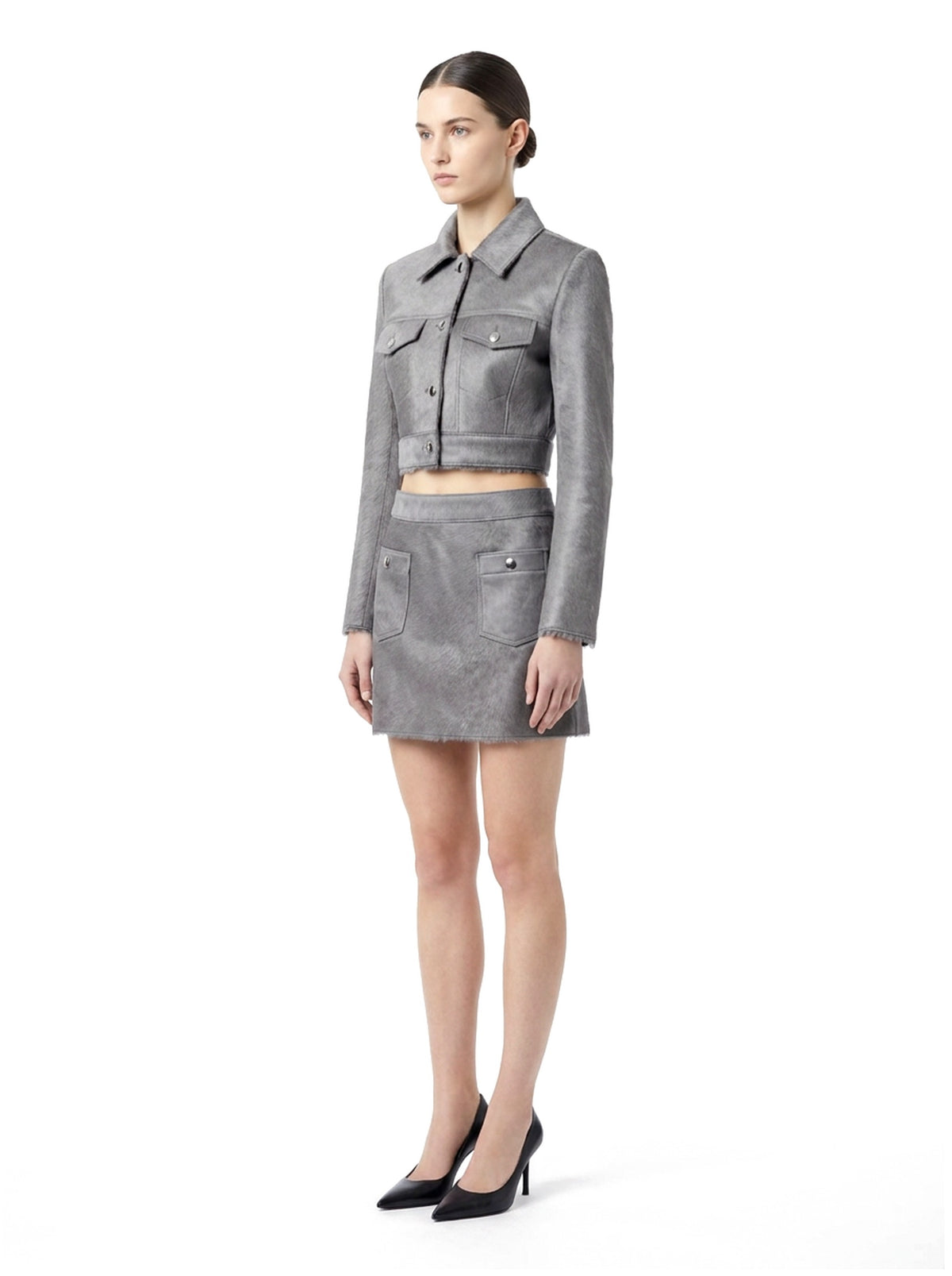 Ensemble veste courte et jupe courte en poil de veau à ras gris, porté par un mannequin, vue trois-quarts.