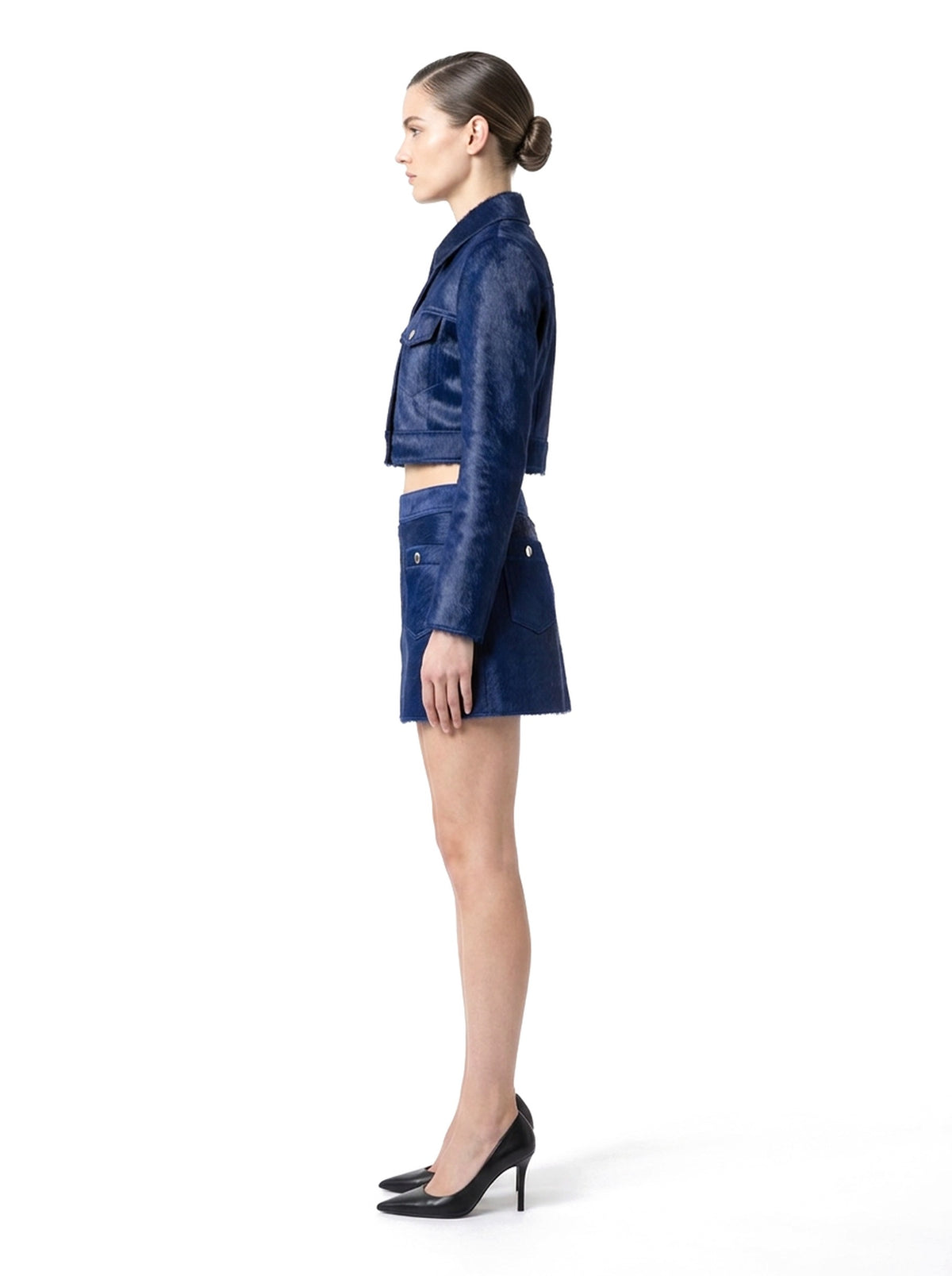 Ensemble veste courte et jupe courte en poil de veau à ras marine, porté par un mannequin, vue de profil.