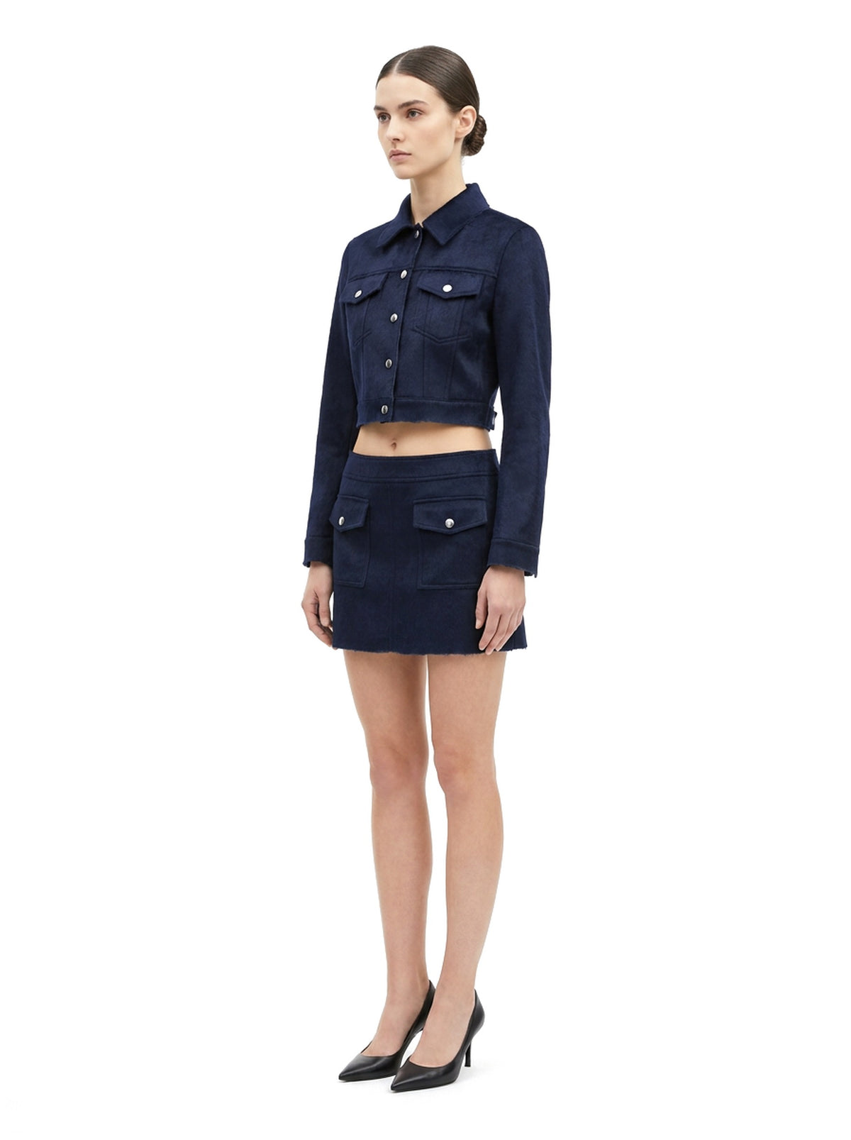 Ensemble veste courte et jupe courte en poil de veau à ras marine, porté par un mannequin, vue trois-quarts.