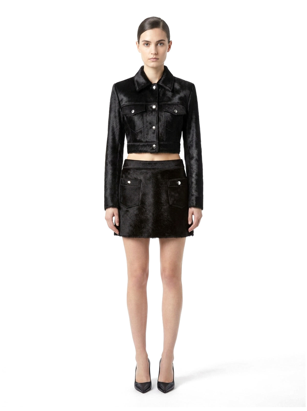 Ensemble veste courte et jupe courte en poil de veau à ras noir, porté par un mannequin, vue de face.