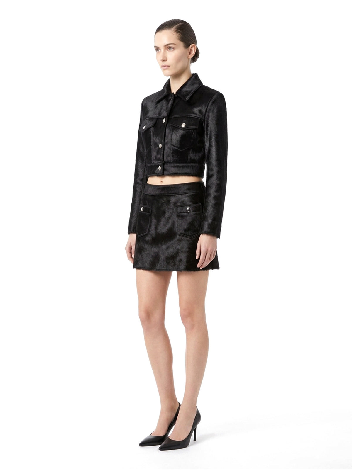 Ensemble veste courte et jupe courte en poil de veau à ras noir, porté par un mannequin, vue trois-quarts.
