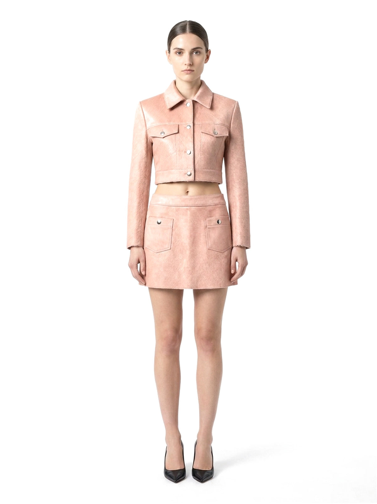 Ensemble veste courte et jupe courte en poil de veau à ras rose, porté par un mannequin, vue de face.