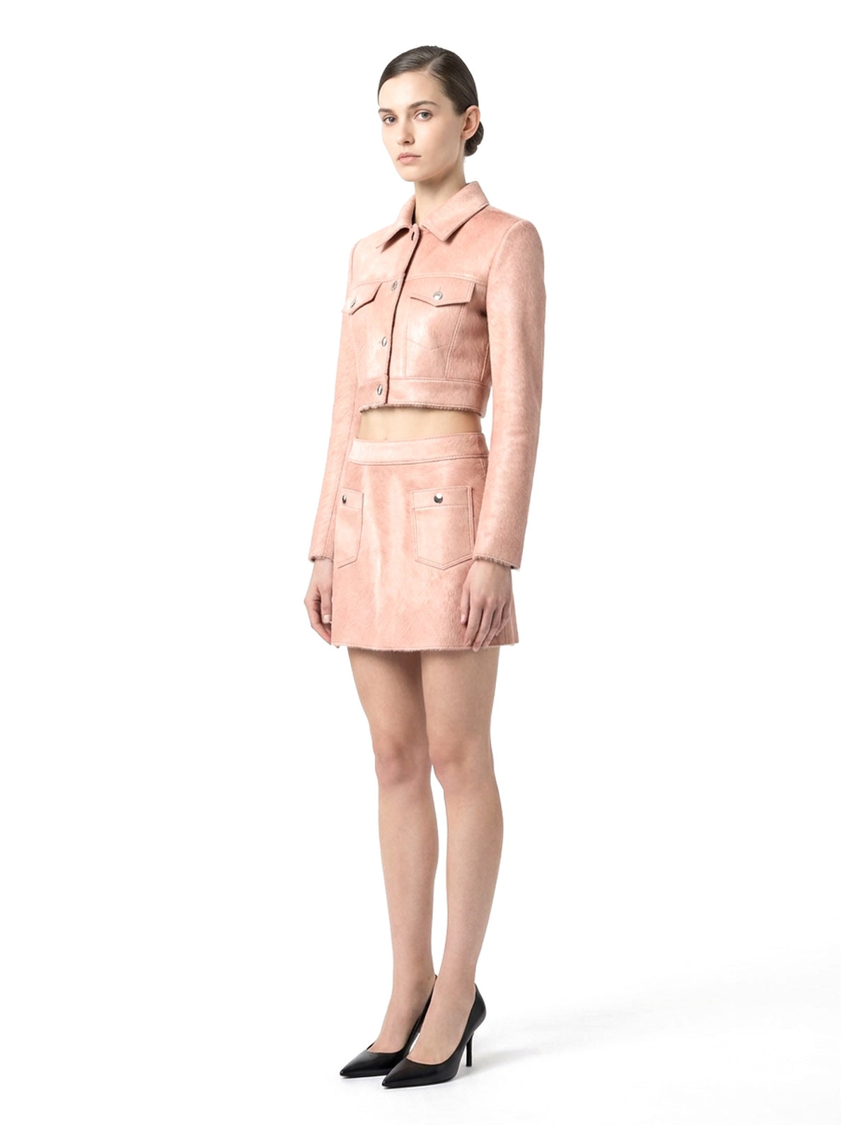 Ensemble veste courte et jupe courte en poil de veau à ras rose, porté par un mannequin, vue trois-quarts.