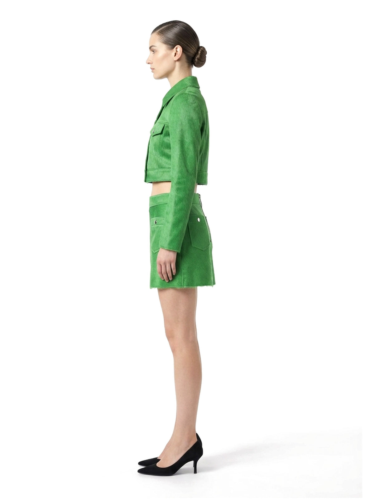 Ensemble veste courte et jupe courte en poil de veau à ras vert, porté par un mannequin, vue de profil.