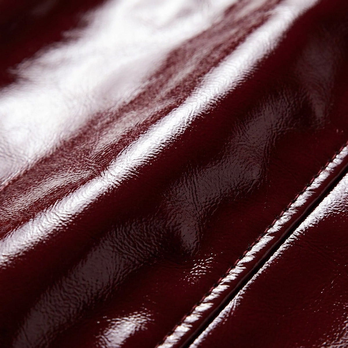 Macro du cuir verni bordeaux et d'un bouton doré, veste RADICE Maison Godefroi